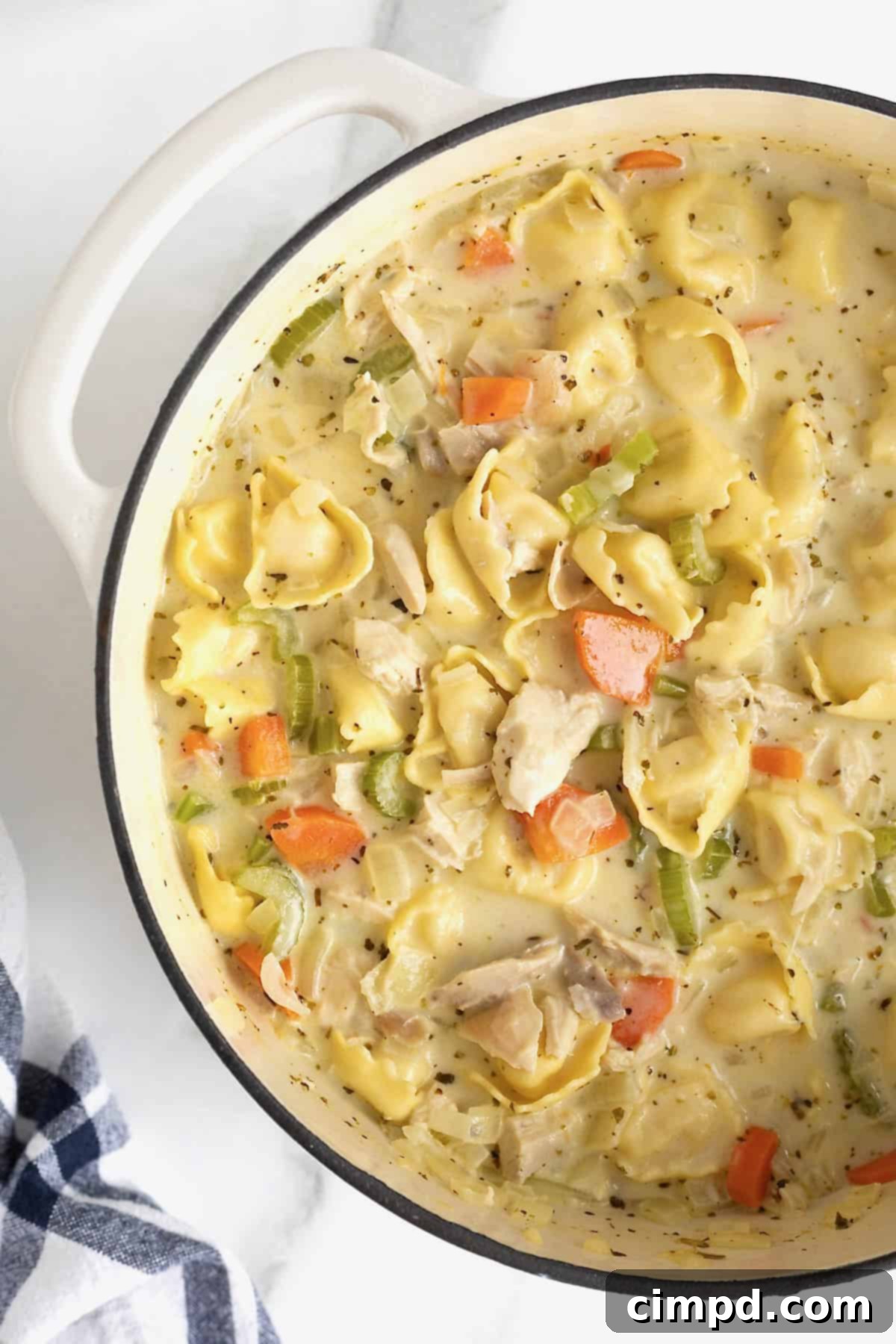 Homestyle Creamy Chicken Tortellini Soup 9 A white Dutch oven of creamy soup with carrots, celery and tortellini pasta.