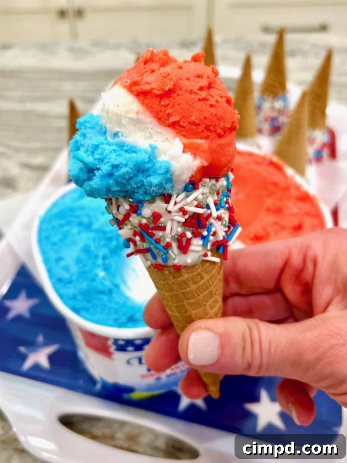 Simple Star-Spangled Bites 5 A close-up of a decorated sugar cone filled with swirls of red, white, and blue ice cream, garnished with patriotic sprinkles, perfect for a summer holiday.