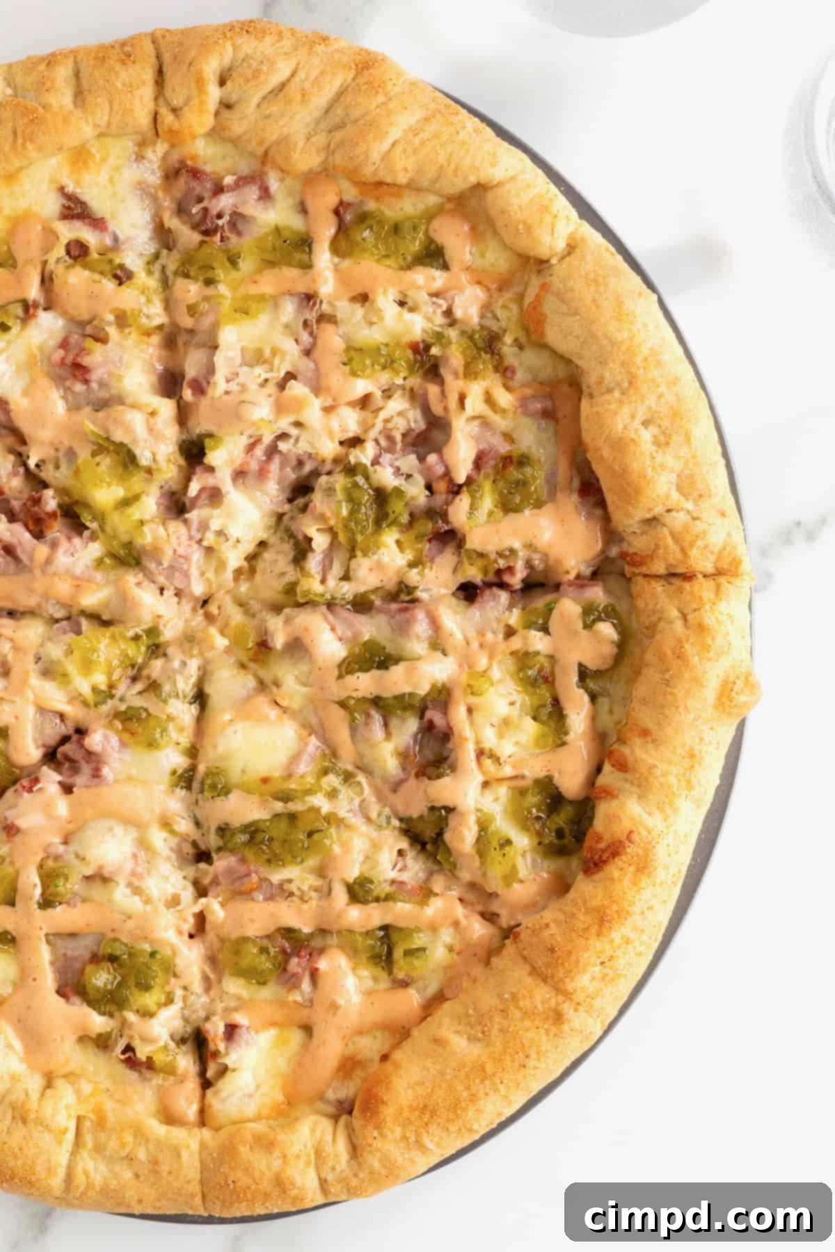 A beautifully presented stuffed crust Reuben pizza on an aluminum pizza pan, ready to be sliced.