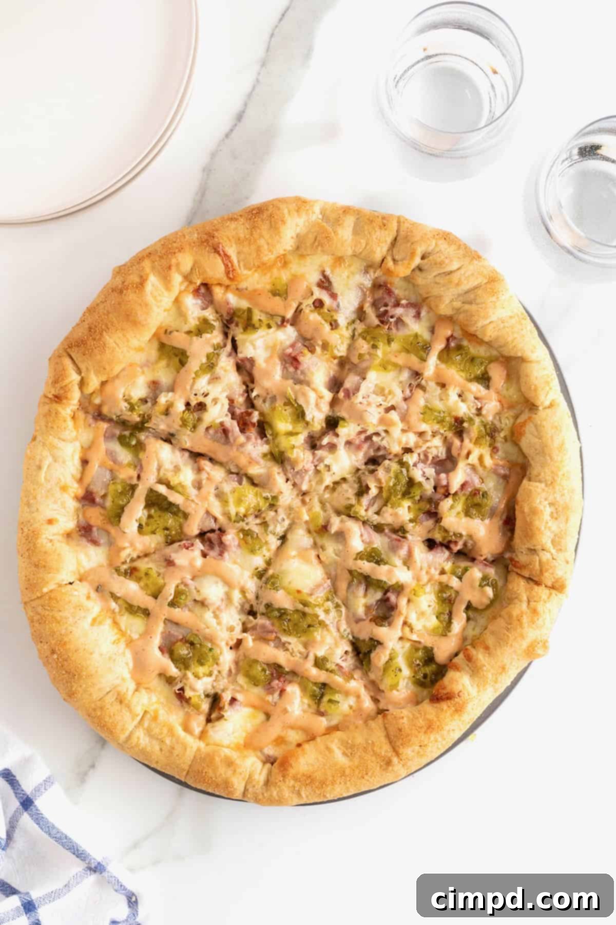 A hot, delicious Reuben pizza, perfectly cut into eight slices on an aluminum pizza pan, ready to be enjoyed.