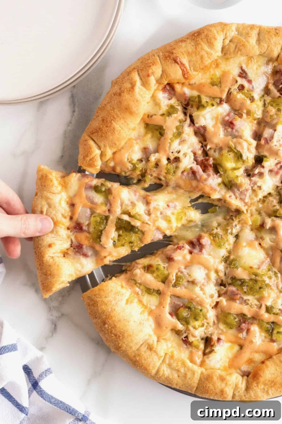 A chef lifting a slice of perfectly reheated Reuben pizza, showing its fresh appearance and melted cheese.