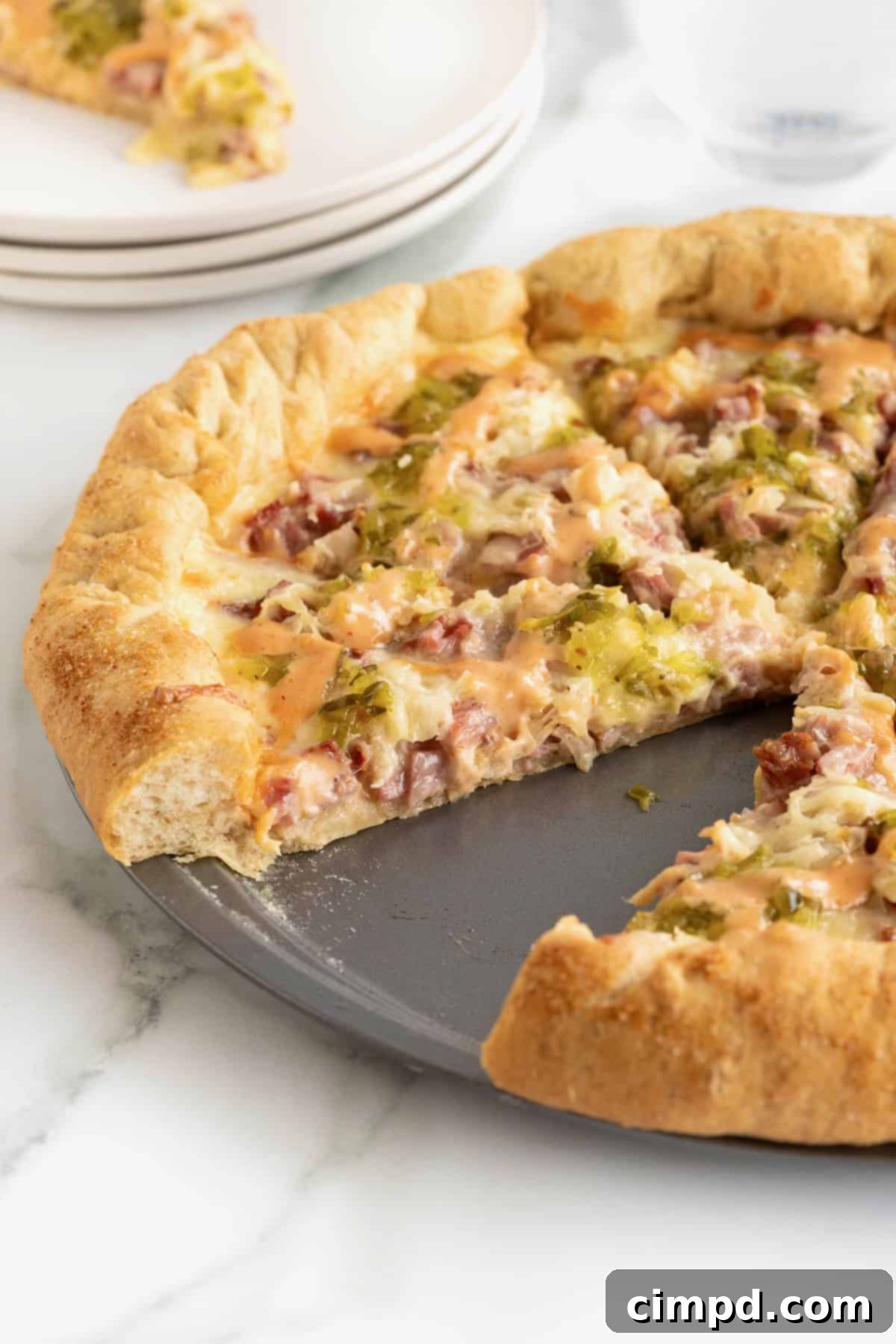 A mouth-watering slice of Reuben pizza missing from a whole pizza, showcasing the rich toppings and stuffed crust.