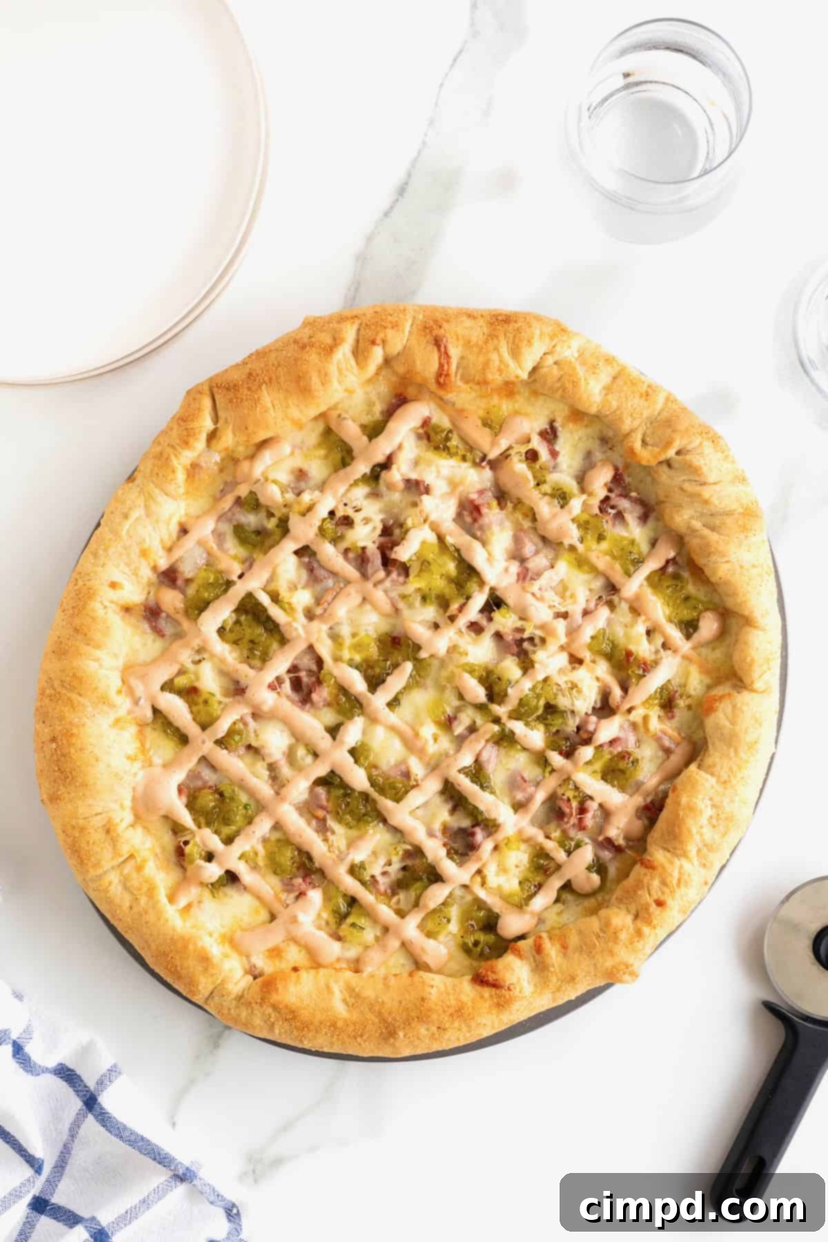 A freshly baked, golden-brown Reuben pizza with a perfectly puffed and cheesy stuffed crust on an aluminum pan.