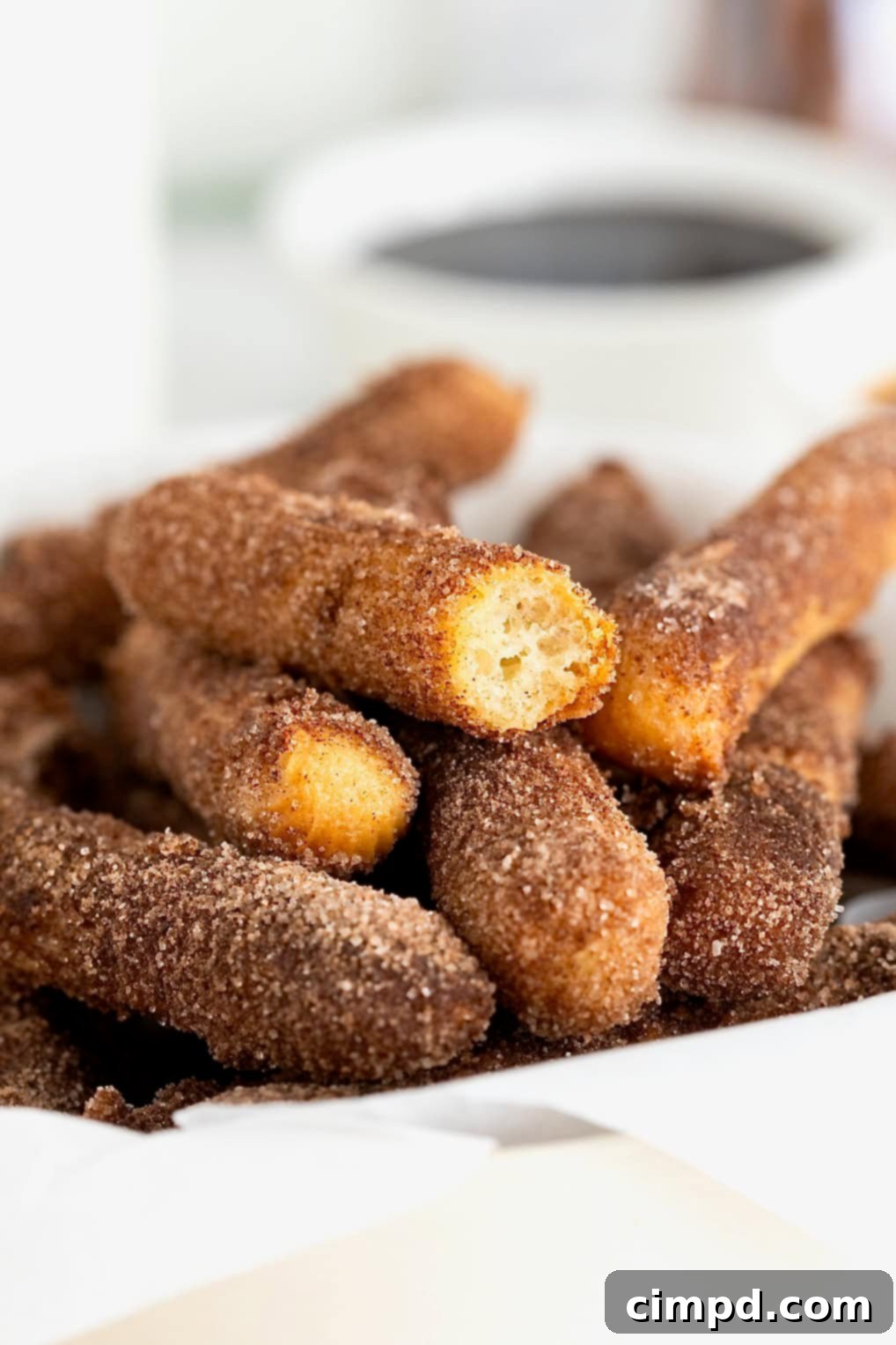 Guilt-Free Baked Churros 4 A bowl of baked churros. The top churro has a bite out of it.