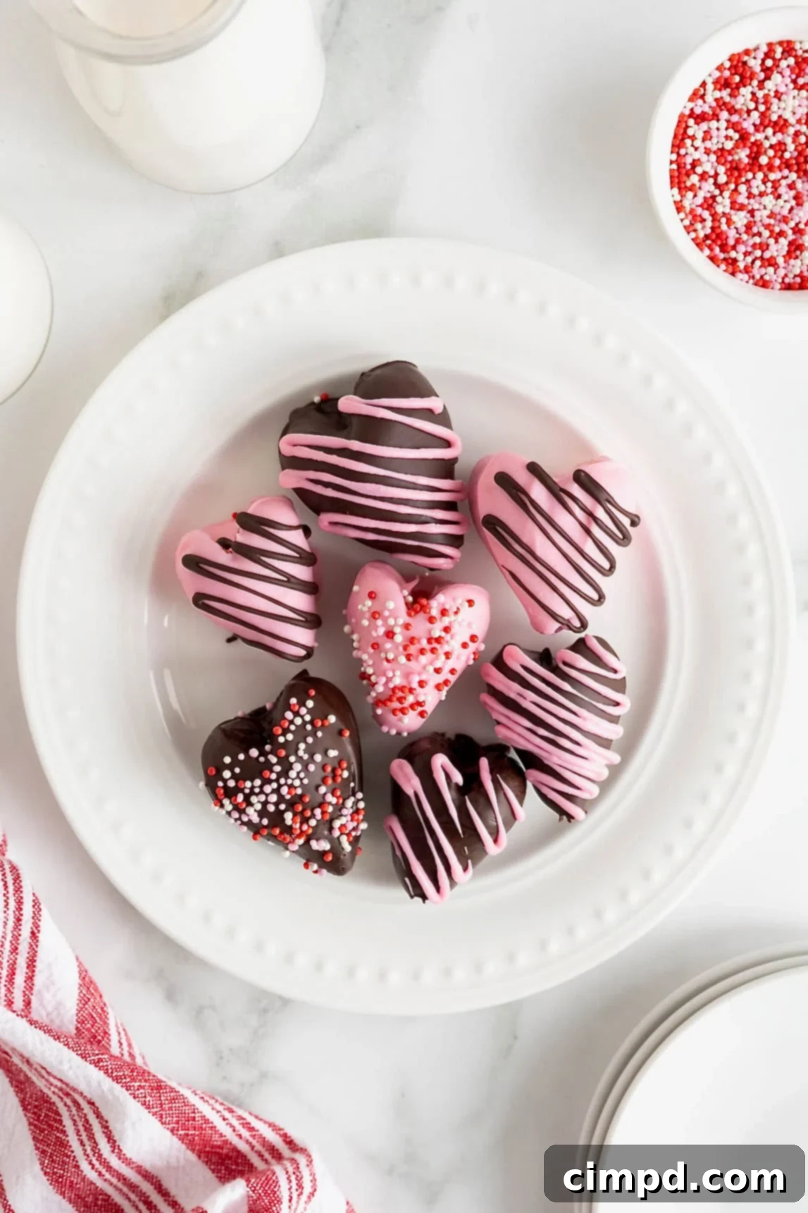 Sweetheart Chocolate Strawberries 2 Seven perfectly arranged heart-shaped chocolate covered strawberries on an elegant white plate, adorned with delicate bead details, creating a beautiful display.