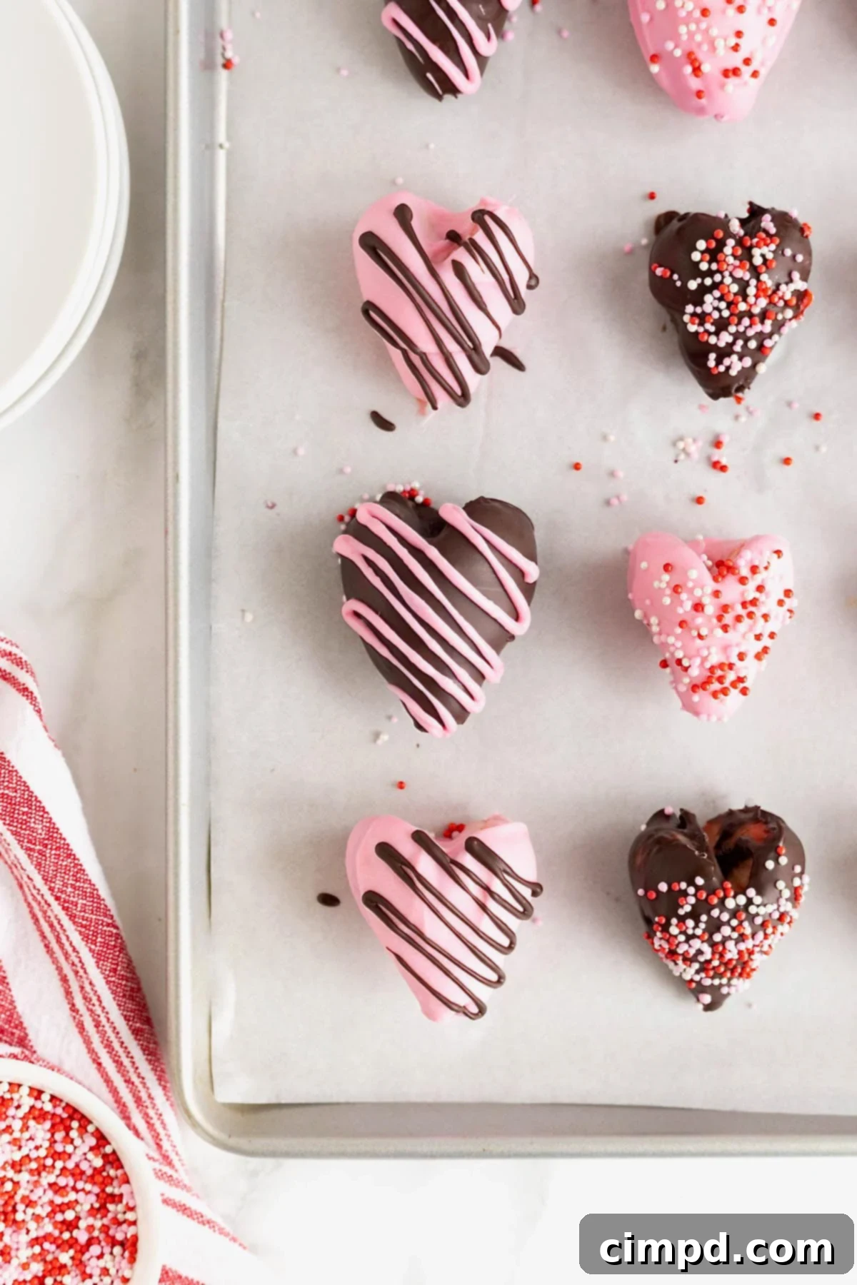 Sweetheart Chocolate Strawberries 11 An array of chocolate-covered heart-shaped strawberries, carefully laid out on a parchment-lined aluminum baking sheet, showcasing their festive appeal.