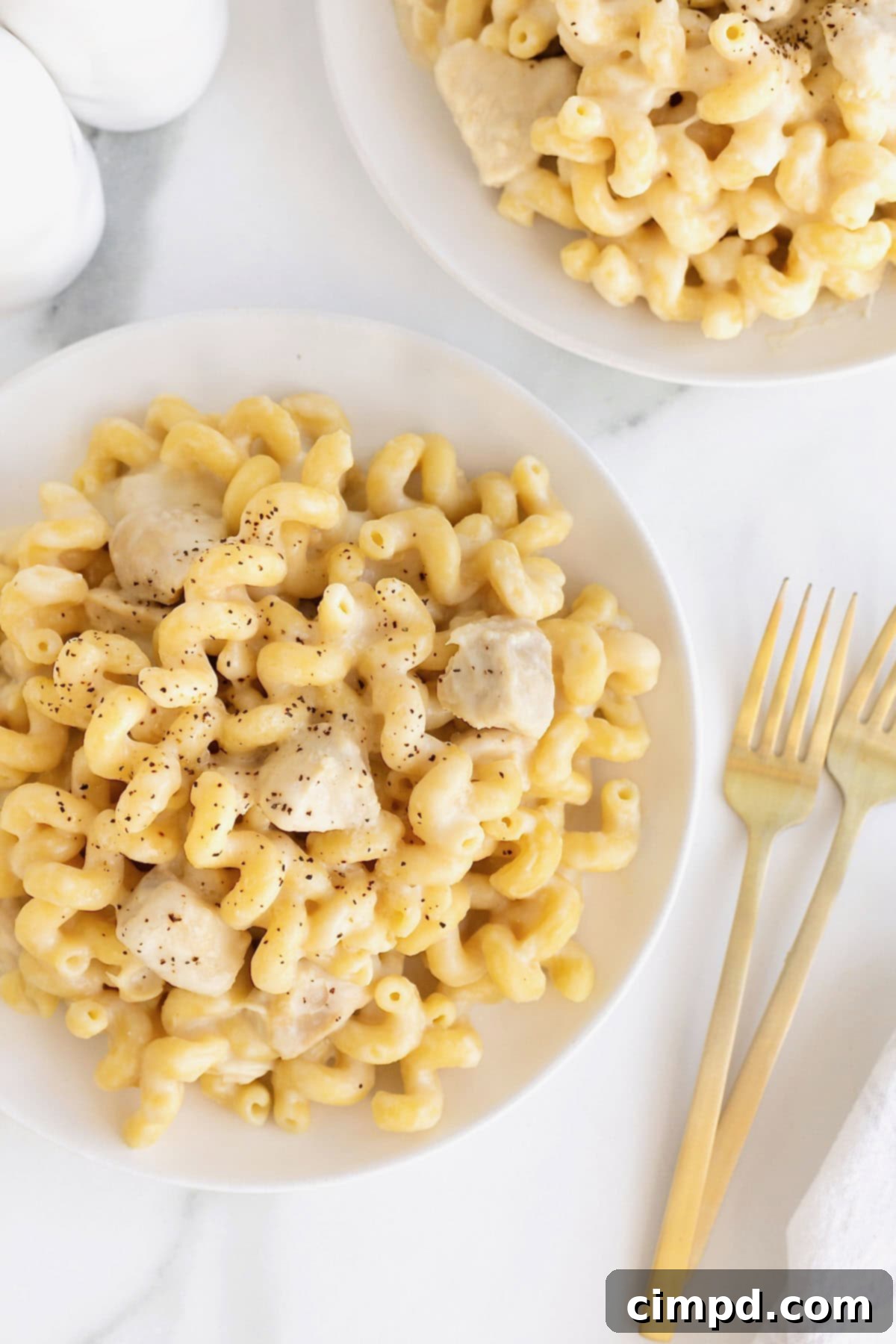 A large white dinner plate of chicken Alfredo pasta.
