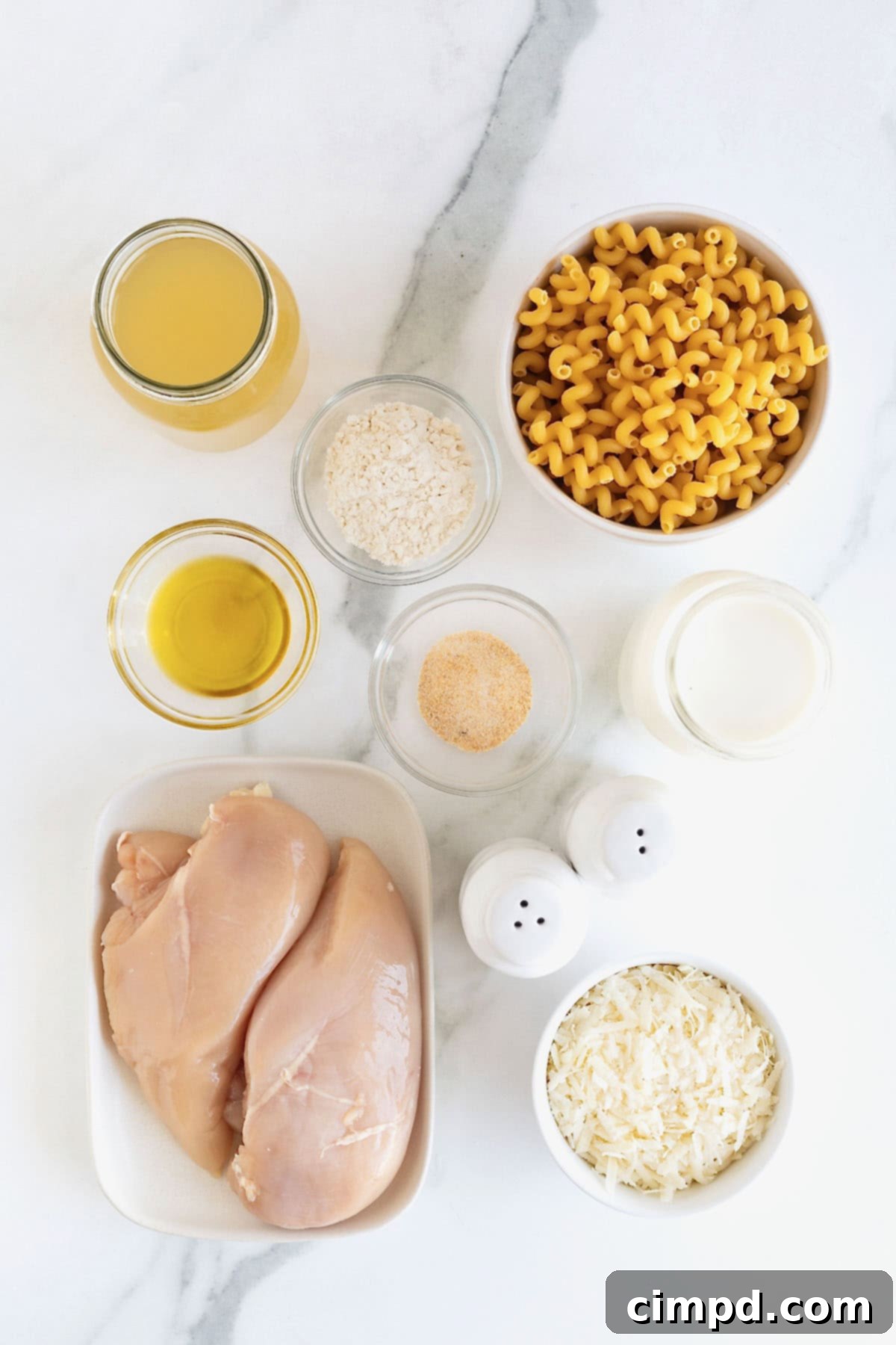 Ingredients to make one pot chicken Alfredo pasta in small glass dishes on a white marble counter.
