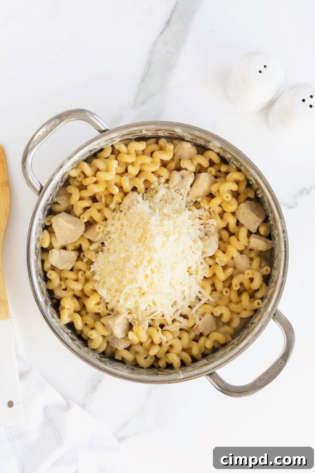 Grated parmesan cheese added to a pot of chicken Alfredo pasta.