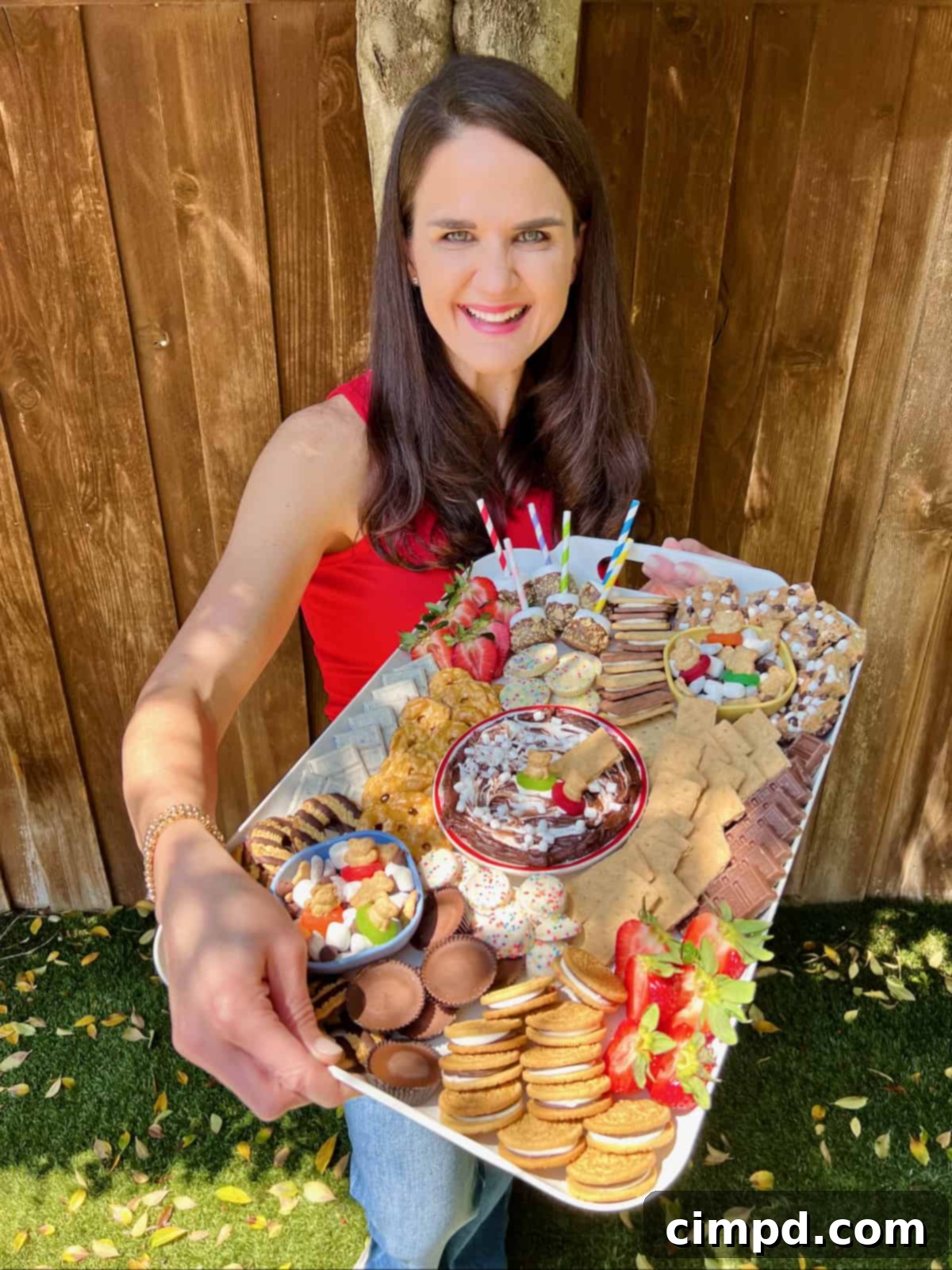 Kids Summer Smores Fun Board 3 Maegan Brown, the BakerMama, smiles brightly while holding the colorful and inviting kid-friendly s'mores board, ready for a summer celebration.