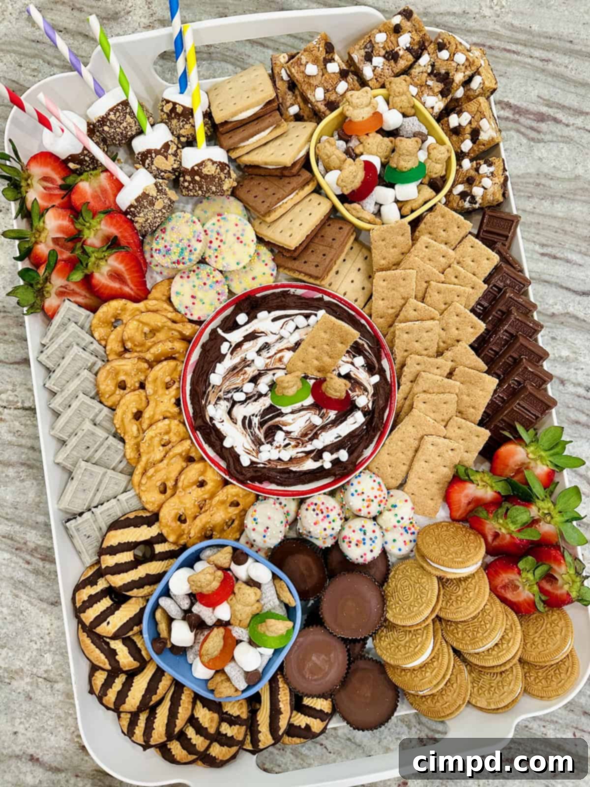 Kids Summer Smores Fun Board 7 The fully assembled kid-friendly S'mores board, overflowing with an array of chocolate, marshmallow, and graham cracker treats, rests on a dark grey marble counter, showcasing a perfect summer dessert display.