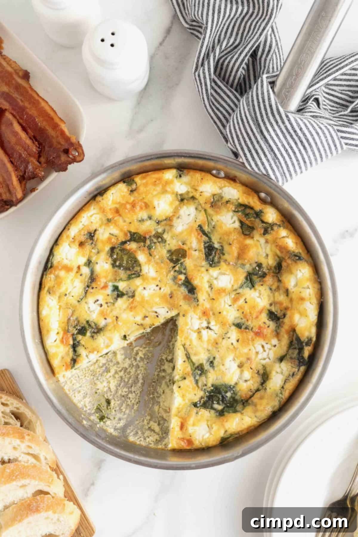 A vibrant Red Pepper, Spinach, and Goat Cheese Frittata resting in an aluminum pan on a white marble counter, ready to be served.