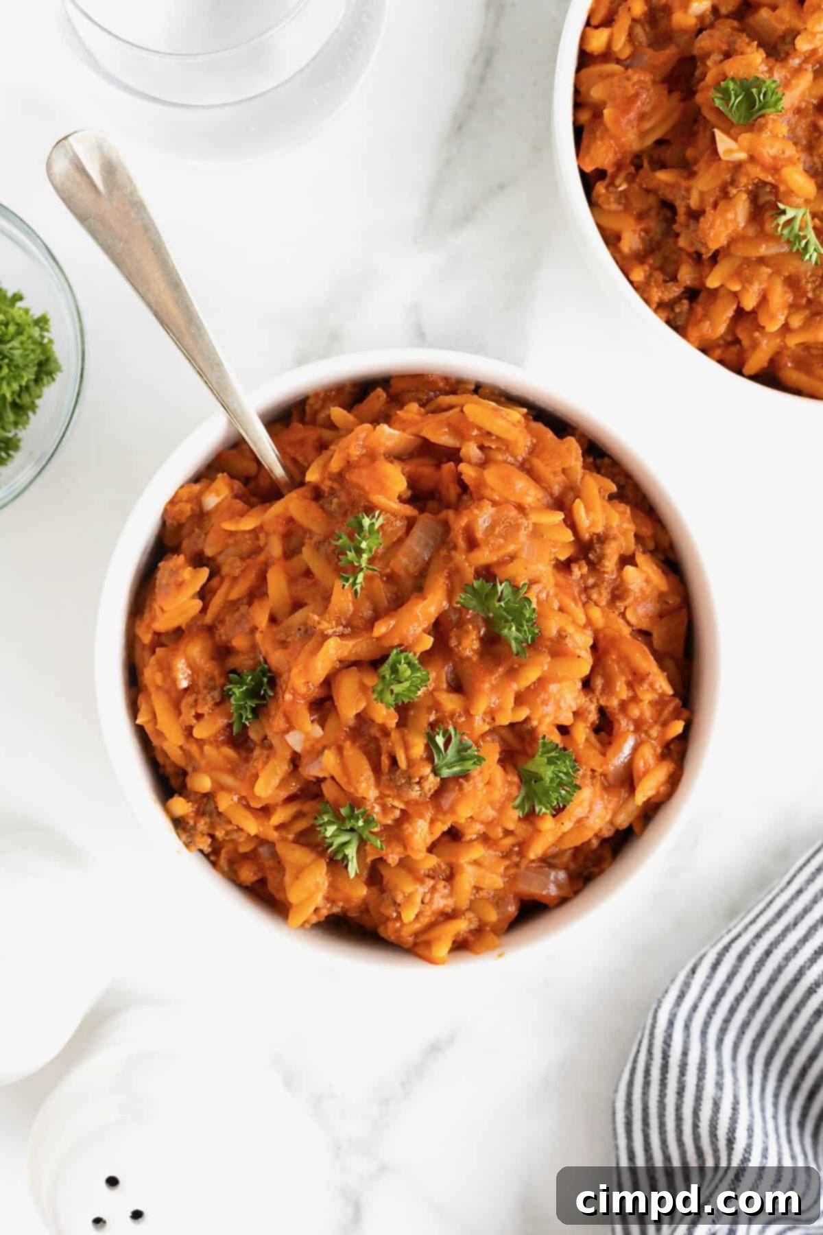 One-Pot Sloppy Joe Orzo 3 A small white bowl of sloppy Joe orzo on a white marble counter.
