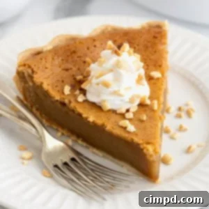 A delicious piece of baked peanut butter pie, garnished with whipped cream and chopped peanuts, presented on a white plate with two forks.