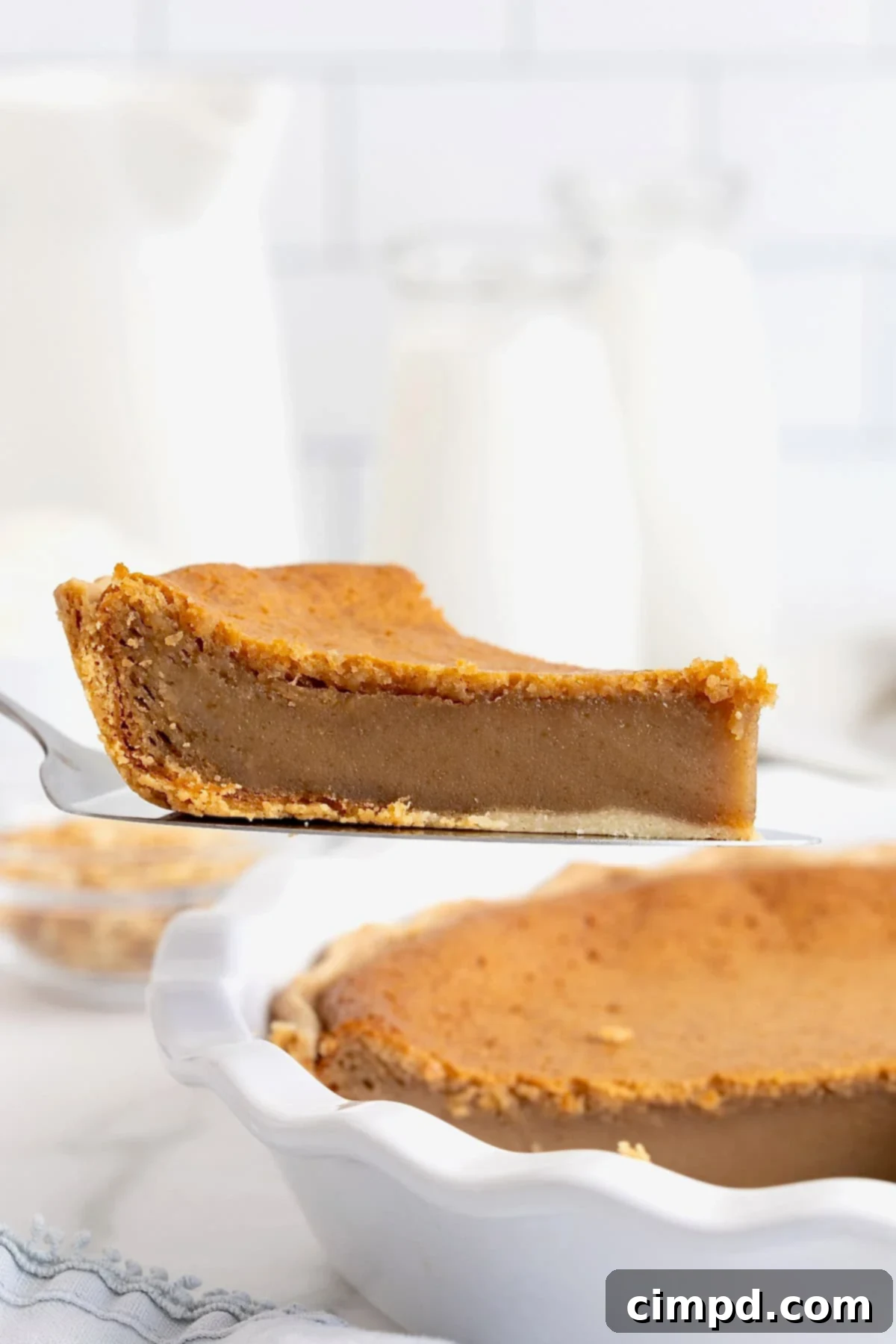 A delectable slice of peanut butter pie being carefully lifted from a white glass pie plate with a metal spatula, ready to be served.