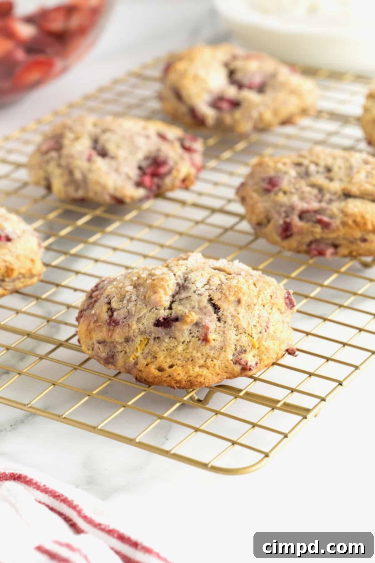 Scone Strawberry Shortcake 4 Five strawberry scones on a gold-toned metal cooling rack on a white marble counter.