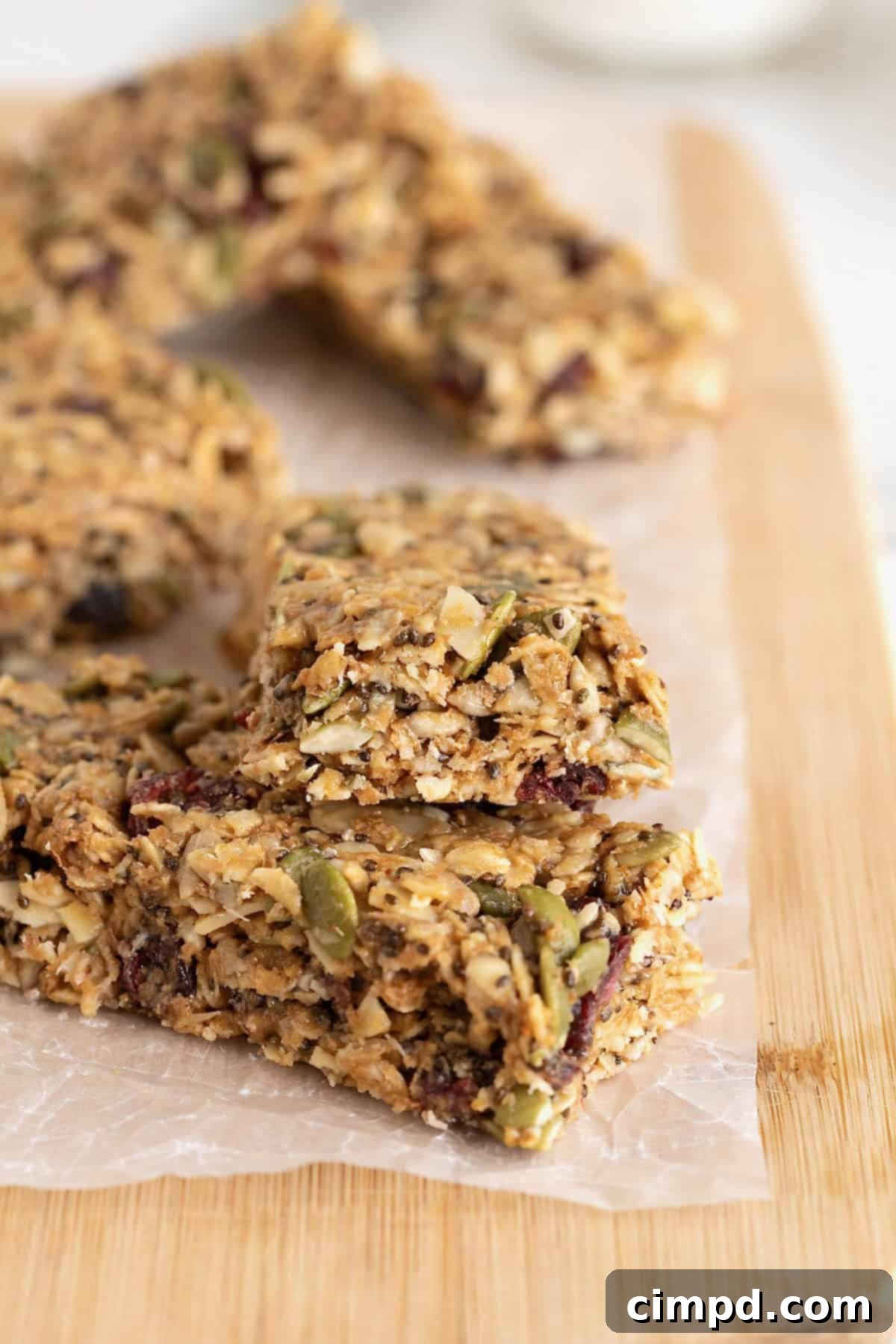 A stack of delicious no-bake power bars on a parchment-lined cutting board, with one bar showing a tempting bite taken out.