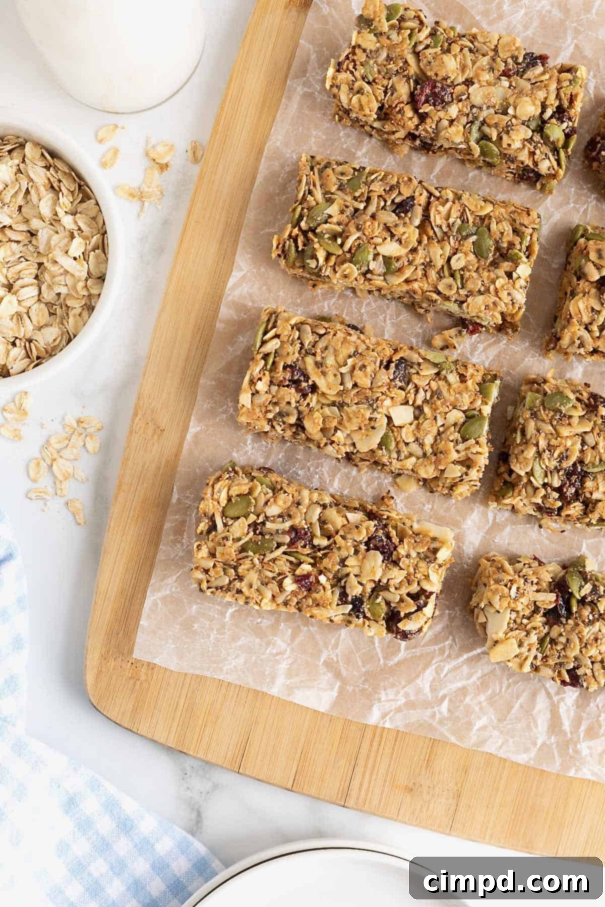 Six homemade snack bars neatly presented on a parchment-lined wooden cutting board, showcasing their wholesome texture.