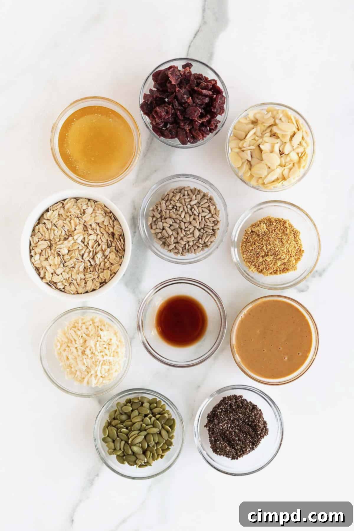 A vibrant display of fresh ingredients for No-Bake Power Bars, neatly arranged in small glass dishes on a pristine white marble counter, ready for preparation.