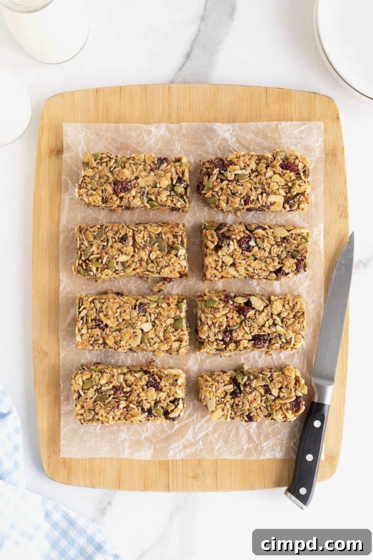 Eight perfectly cut power bars arranged on a parchment-lined wooden cutting board, next to a small sharp knife, ready for serving.