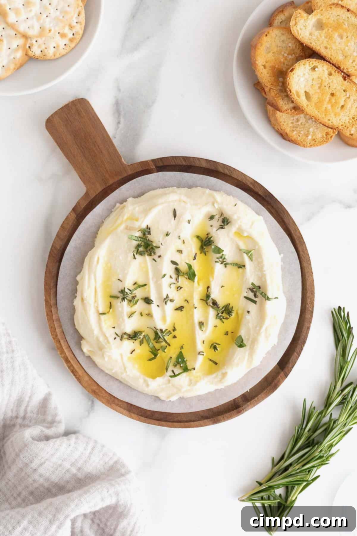 Creamy Whipped Brie 9 Whipped brie artfully arranged on a wooden serving plate, beautifully garnished with a generous drizzle of olive oil, vibrant fresh herbs, and a delicate sprinkle of flaky sea salt, creating an enticing savory appetizer.