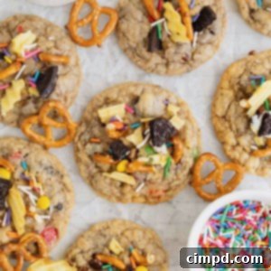 Kitchen sink cookies on a parchment lined surface next to a small bowl of confetti sprinkles.