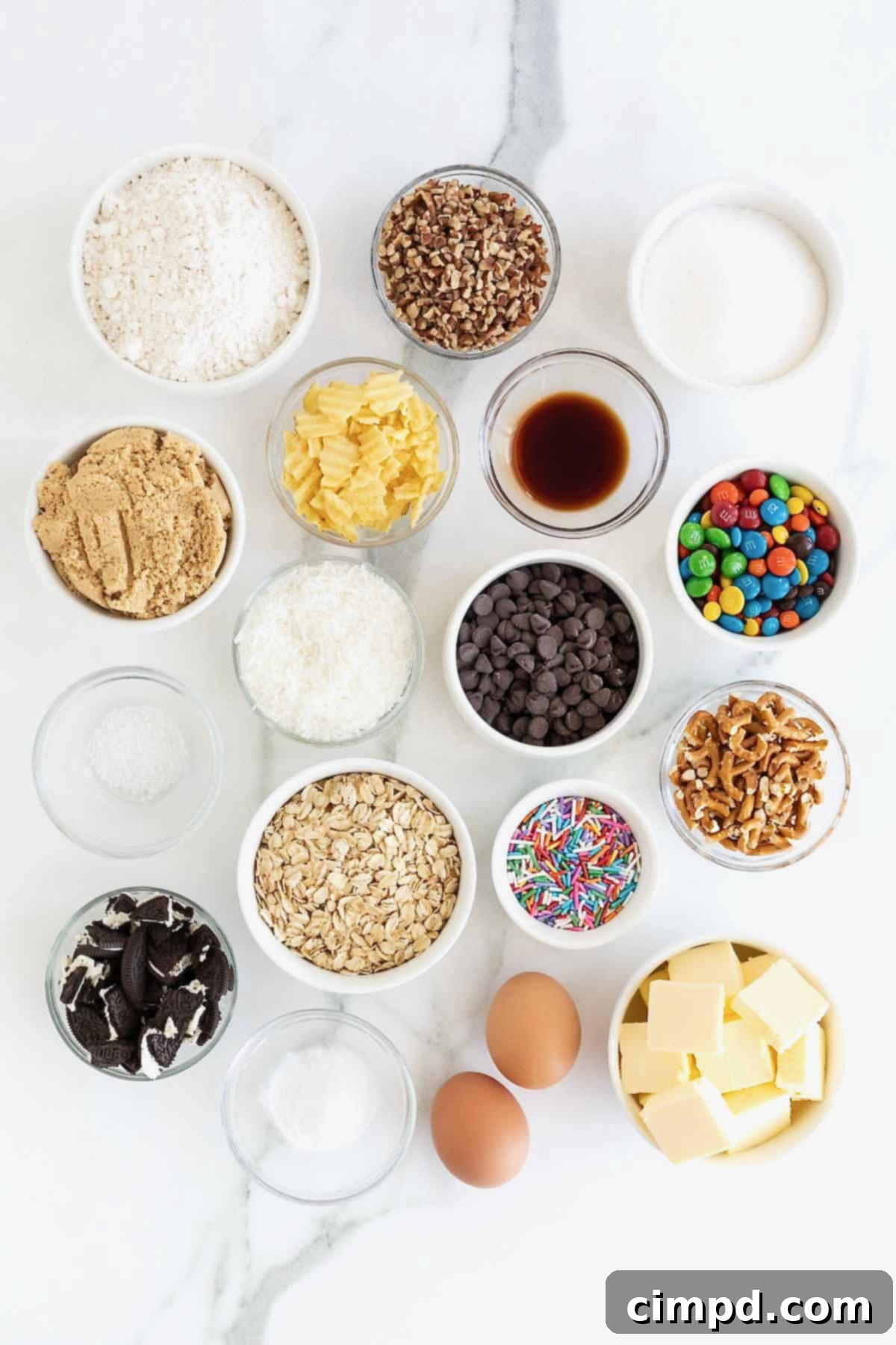Ingredients to make Kitchen Sink Cookies in small glass dishes on a white marble counter.