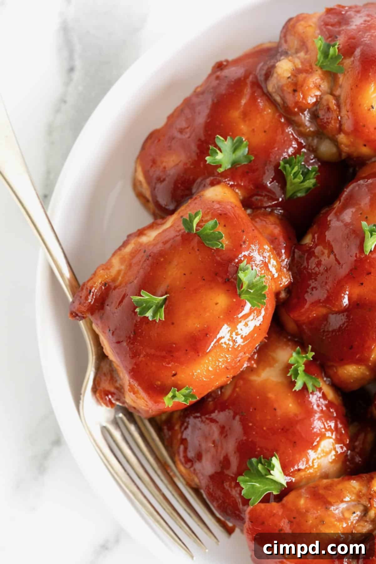 A large white rimmed serving plate of barbecue chicken thighs.
