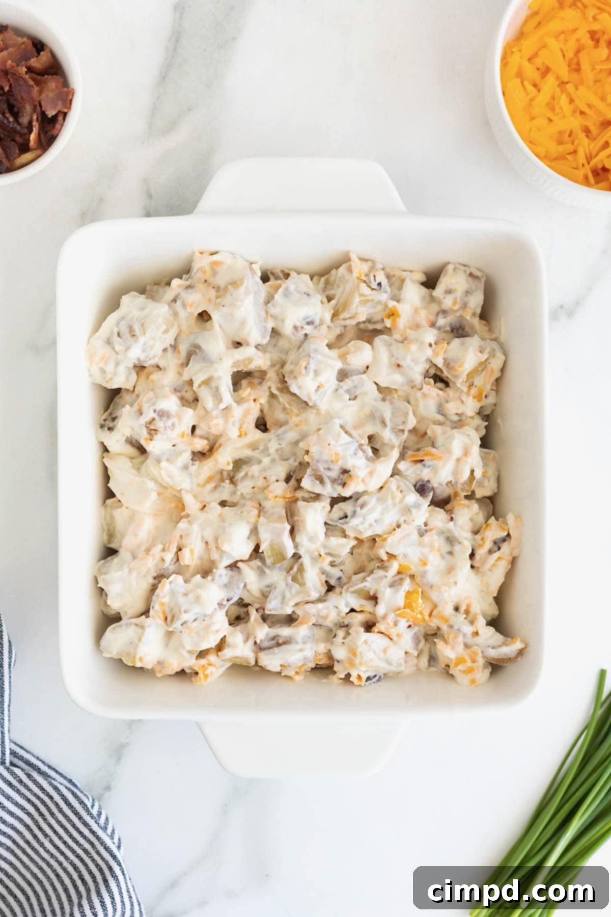 Potatoes in a sour cream sauce in a square white baking dish. 