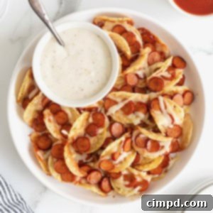 A large rimmed white serving plate piled with pizza taco bites. There is a small white dish of ranch dipping sauce.
