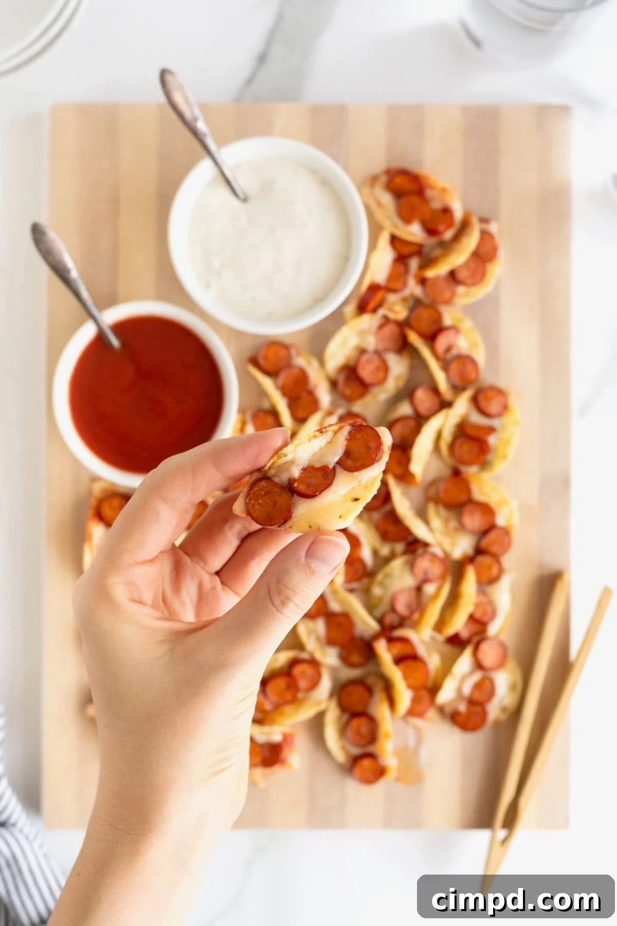 A hand holding a pizza taco bite.