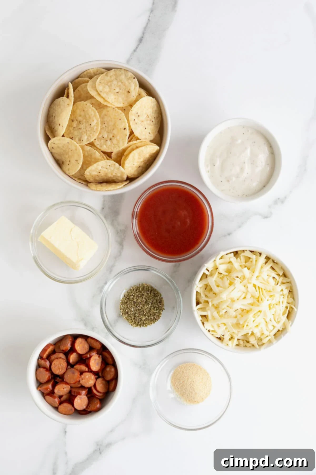 Ingredients to make pizza taco bites in small glass dishes on a white marble counter.