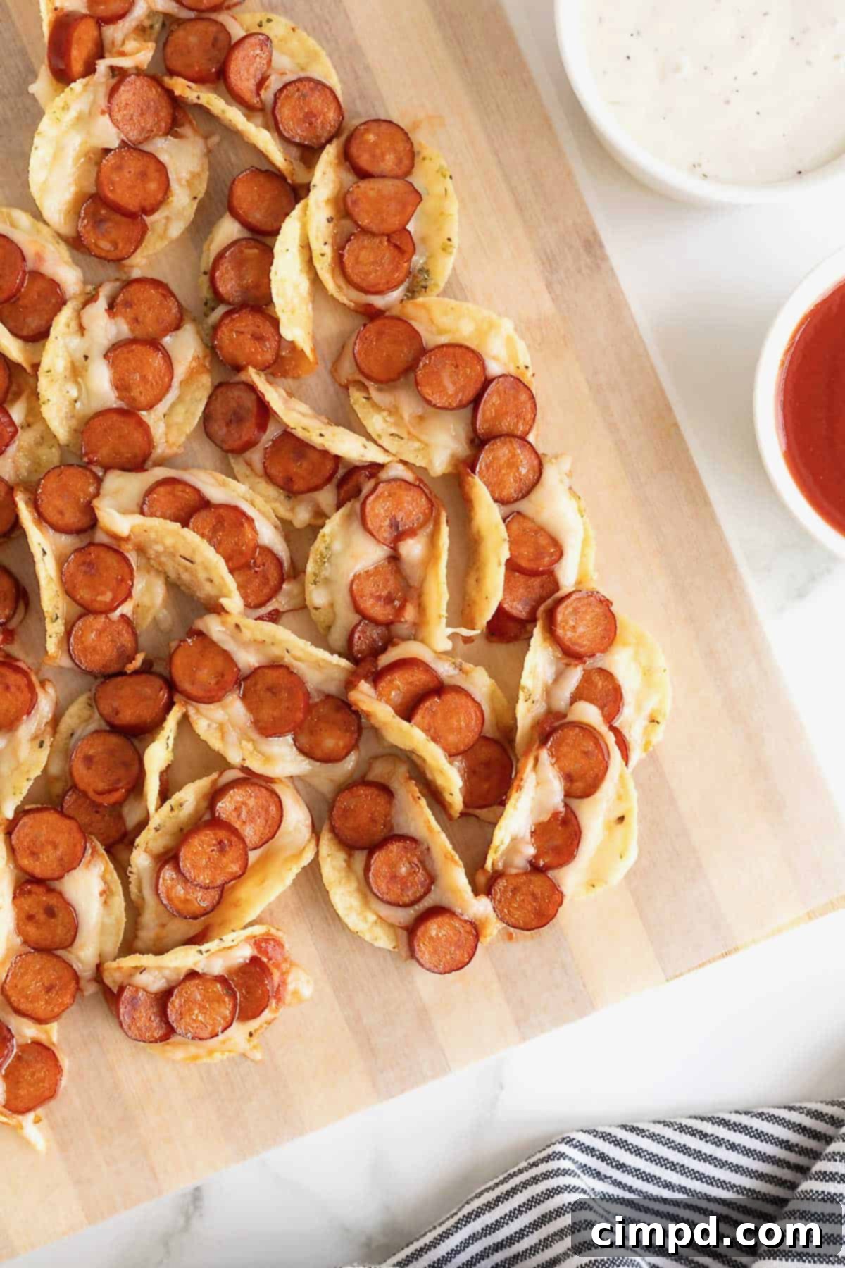 A pile of pizza taco bites on a parchment lined wooden cutting board.