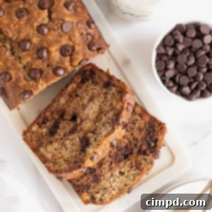 A loaf of brown butter banana bread studded with chocolate chips on a white cutting board.