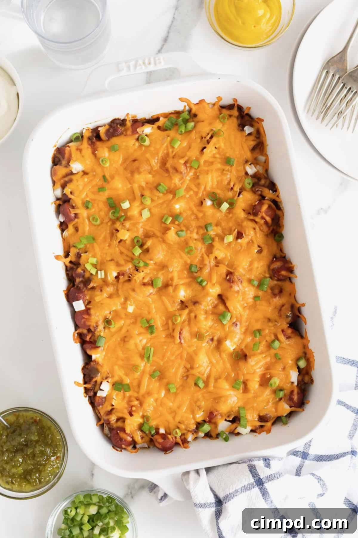 A white casserole dish of chili cheese dog casserole, resting after being baked.