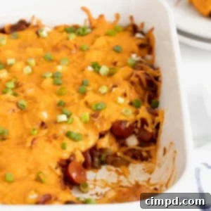 A rectangular white casserole dish of chili cheese dog casserole.