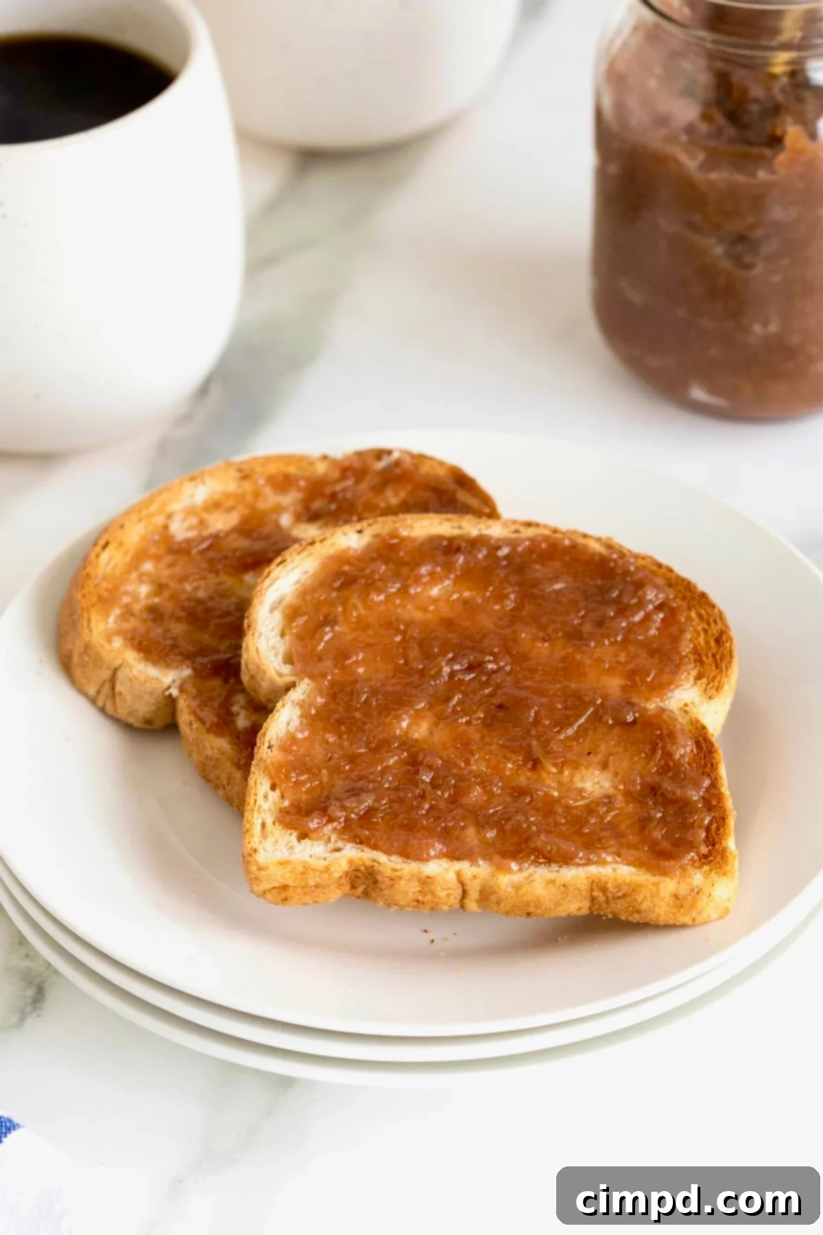 Effortless Homemade Grape Jam 2 Two pieces of toast generously spread with glistening homemade grape jam, resting on a clean white plate, ready to be enjoyed.