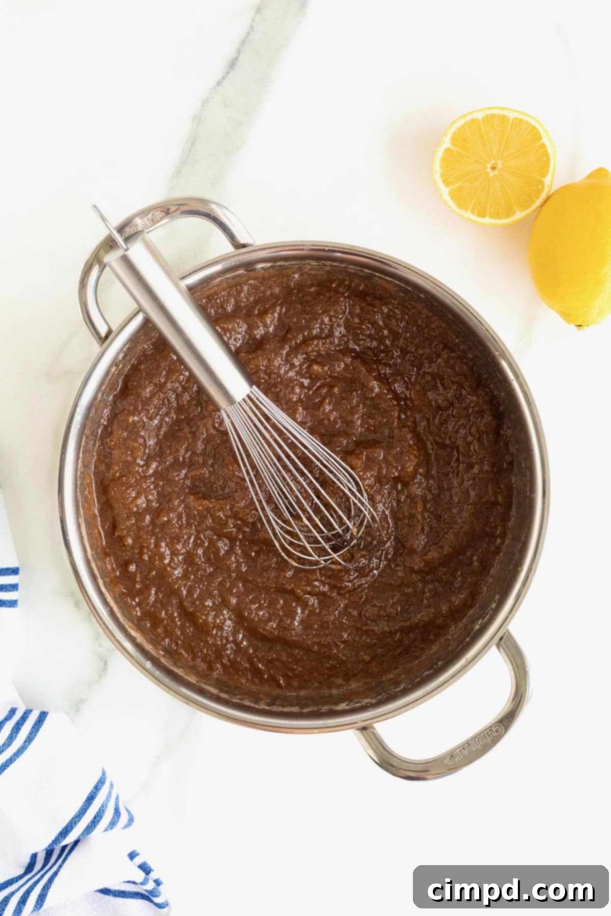 Effortless Homemade Grape Jam 6 A shallow stainless steel pot filled with bubbling homemade grape jam, actively simmering on the stove, showing the reduction process.