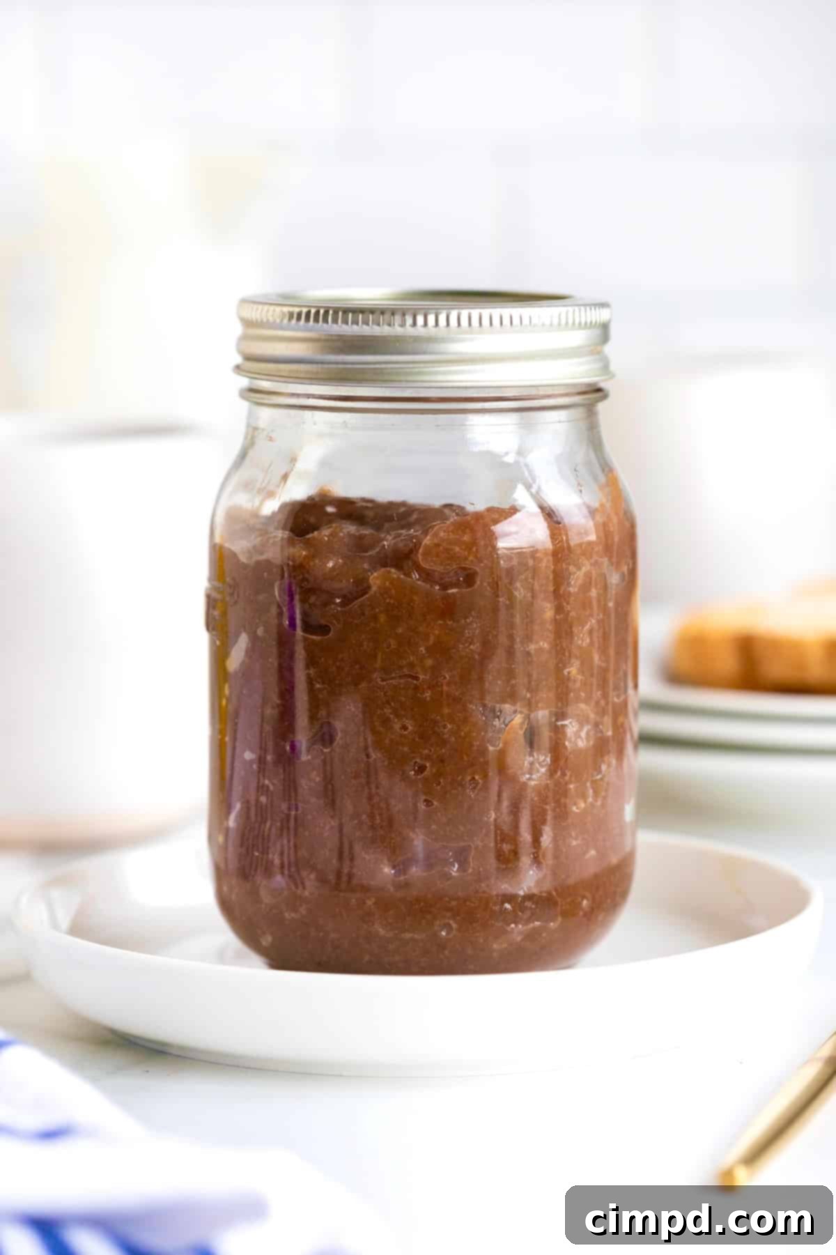 Effortless Homemade Grape Jam 9 A mason jar overflowing with vibrant homemade grape jam, resting on a rustic wooden surface, with a spoon nearby.
