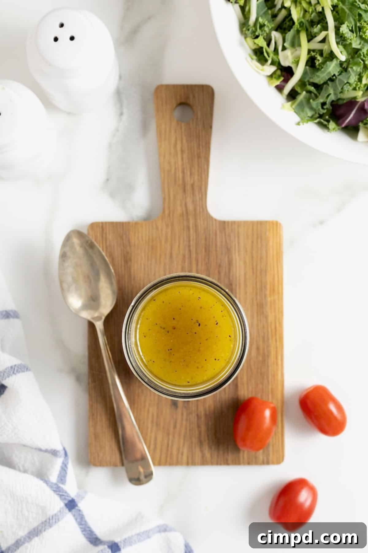 Sparkling Vinaigrette 4 A jar of salad dressing on a rectangular wood cutting board on a white marble counter.