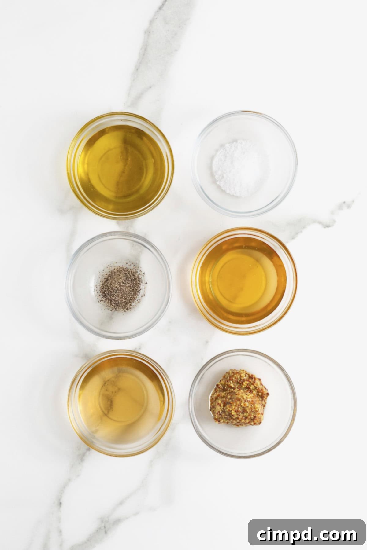 Sparkling Vinaigrette 5 Ingredients to make champagne vinaigrette in small glass dishes on a white marble counter.