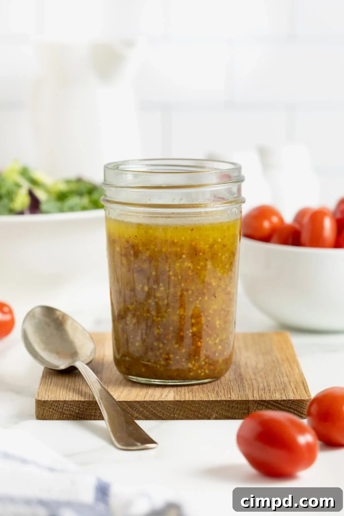 Sparkling Vinaigrette 8 A jar of salad dressing on a rectangular wood cutting board on a white marble counter.