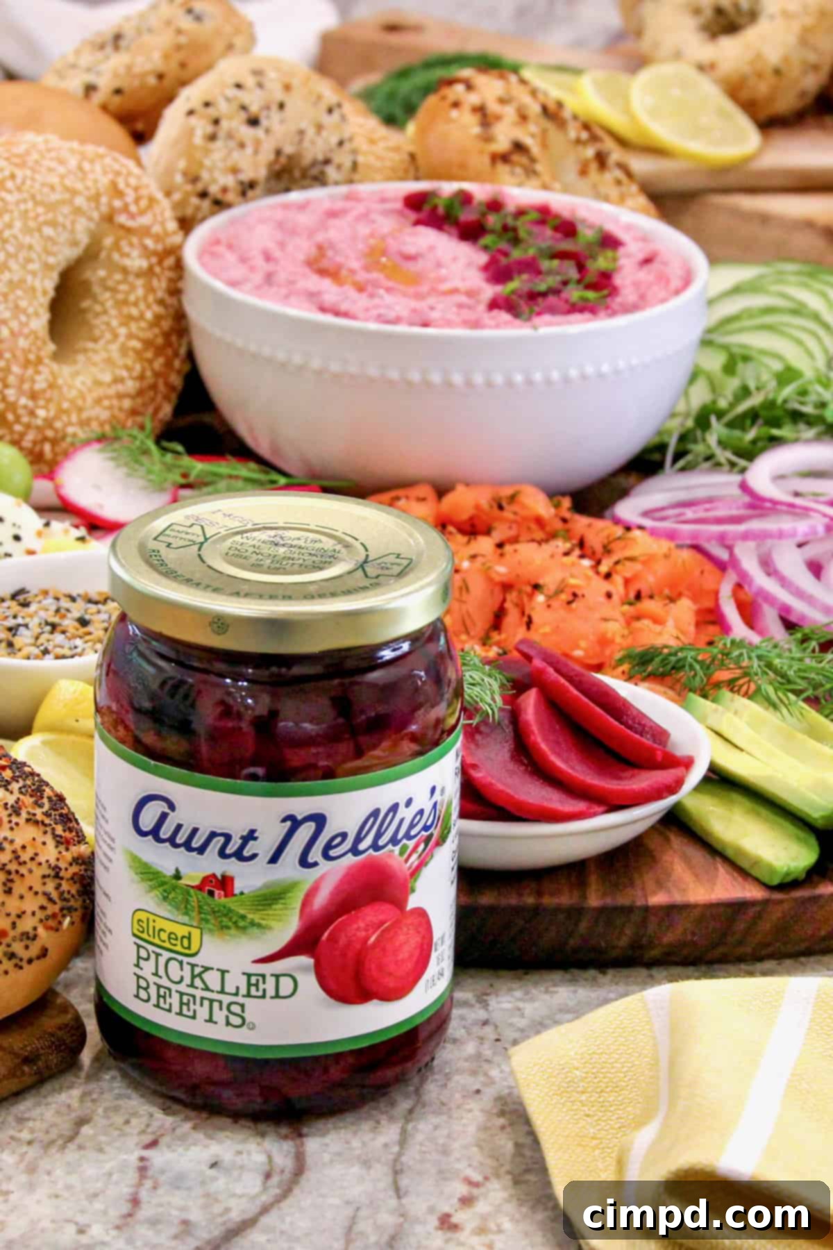 A jar of Aunt Nellie's pickled beets prominently displayed in front of a colorful breakfast bagel sandwich board, highlighting the key ingredient.
