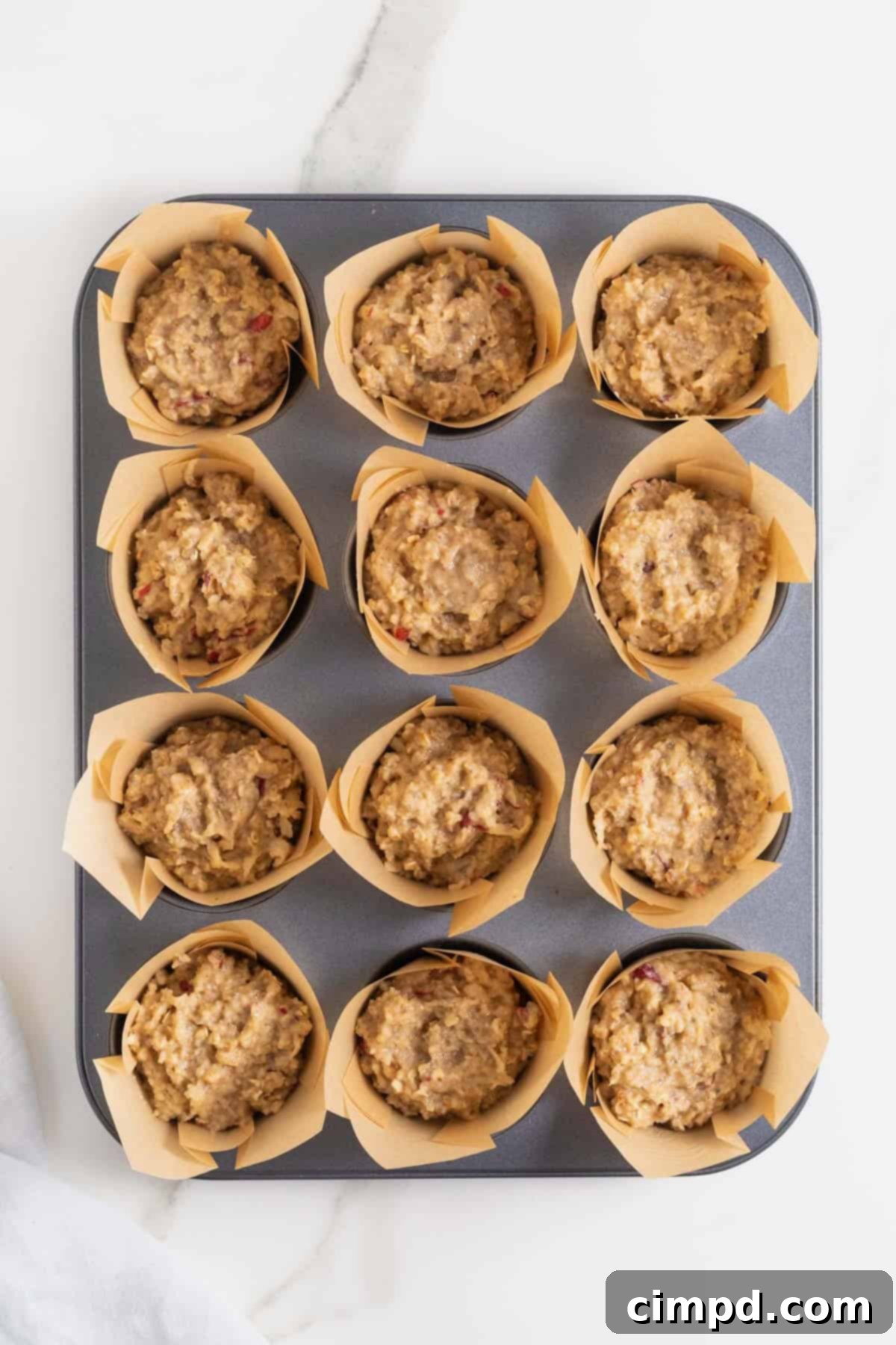 Superfood muffin batter neatly scooped into a muffin tin with brown paper liners, ready for baking.