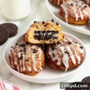 Cinnamon Bun Oreo Fritters 13 A white rimmed plate holding three fried cinnamon rolls with Oreos in the middle. The one of top is cut open to reveal the Oreo inside.