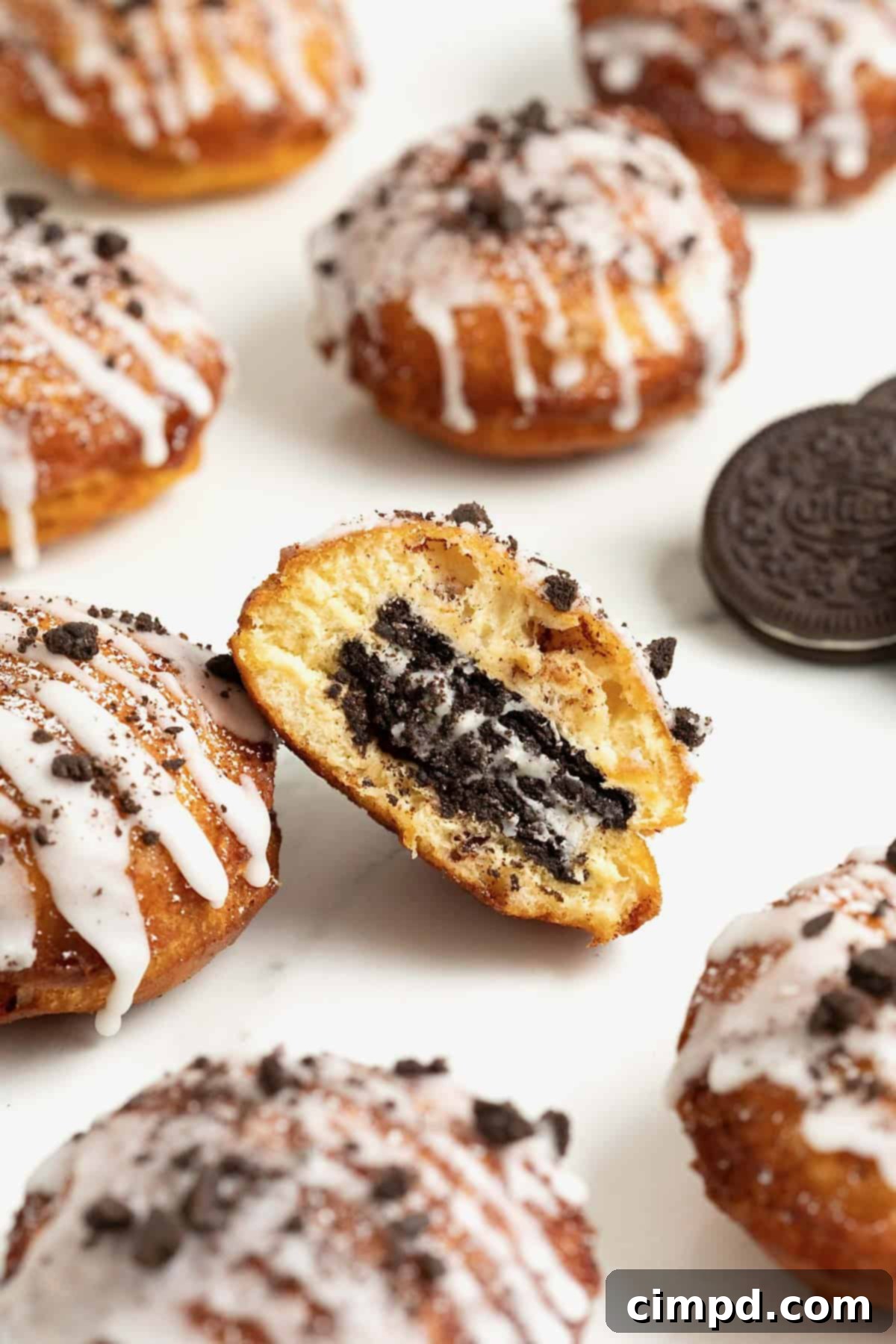 Cinnamon Bun Oreo Fritters 5 Six cinnamon roll fried Oreos on a white marble counter. The center one is cut in half to show the Oreo inside.
