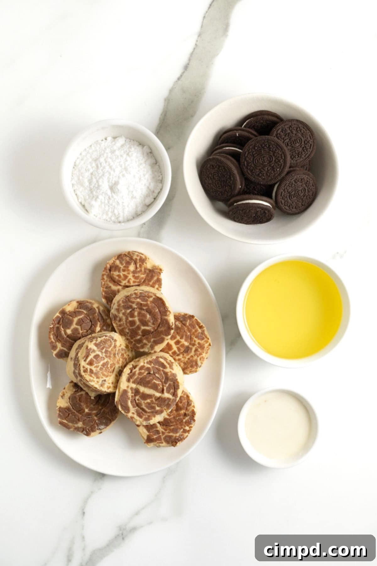Cinnamon Bun Oreo Fritters 6 ingredients to make cinnamon roll deep fried Oreos in small white dishes on a white marble counter.