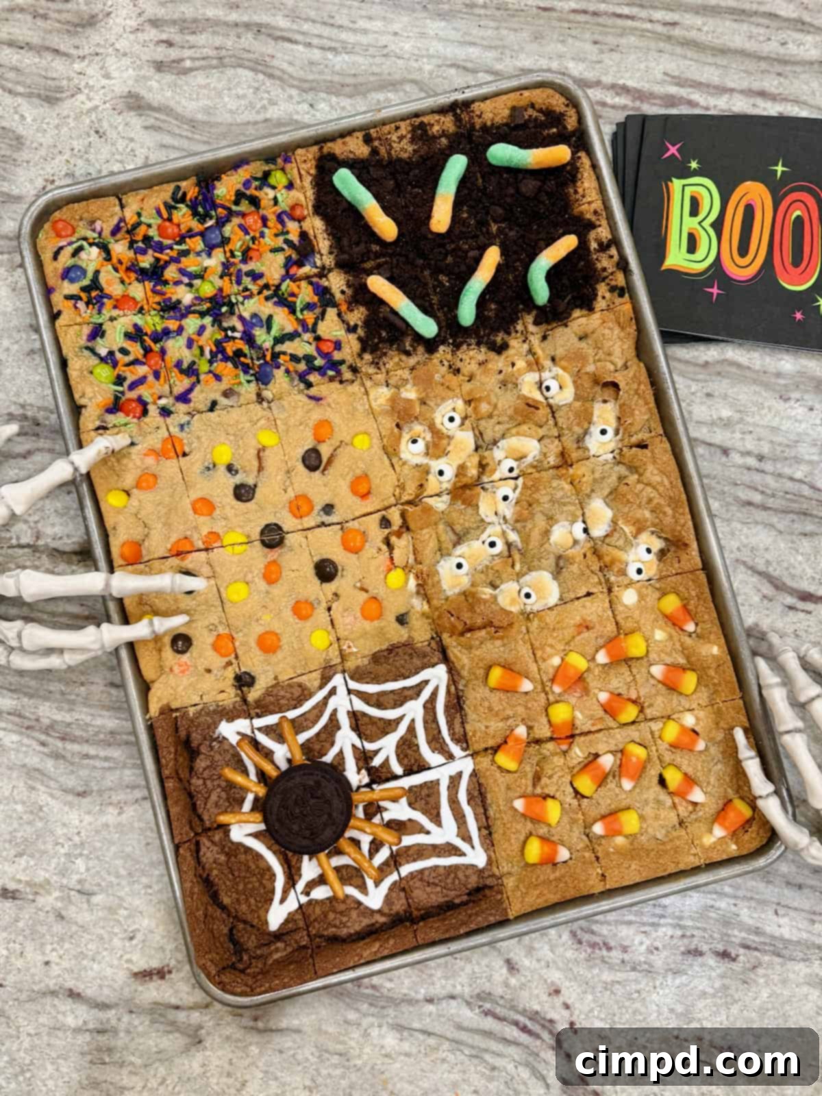 Halloween cookie bars in a sheet pan on a gray and white marble counter, showcasing six distinct Halloween-themed designs.