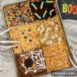 Halloween cookie bars in a sheet pan on a gray and white marble counter, showcasing six distinct Halloween-themed designs.