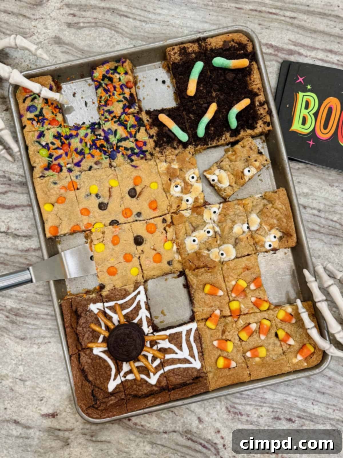 A close-up shot of the Halloween cookie bars, displaying the different decorated sections baked in a single sheet pan on a marble counter.